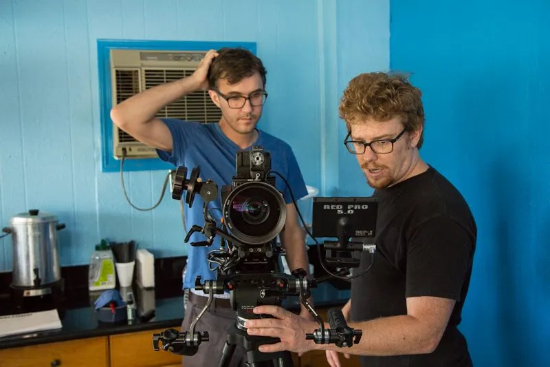 Two crew members set up a RED camera in a bright blue motel kitchenette