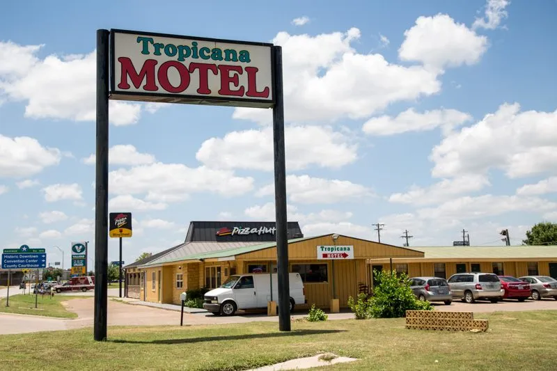 The Tropicana Motel sign under a big Texas sky, the white van parked beyond